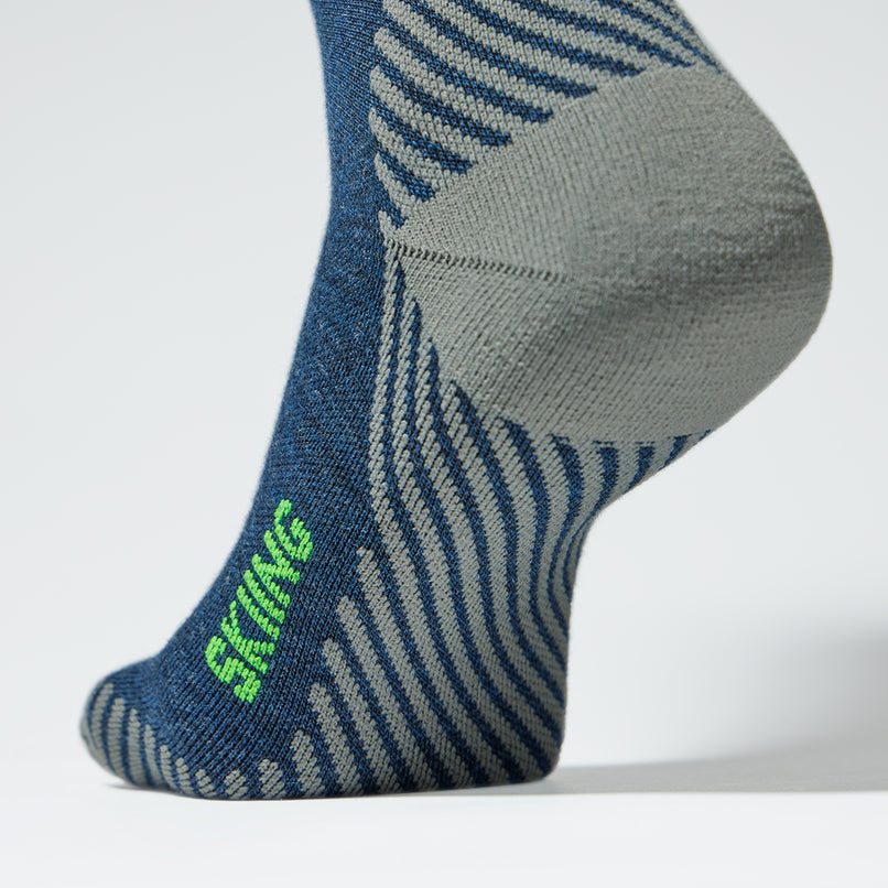 Close up of a blue compression sock with a grey heel and green details.