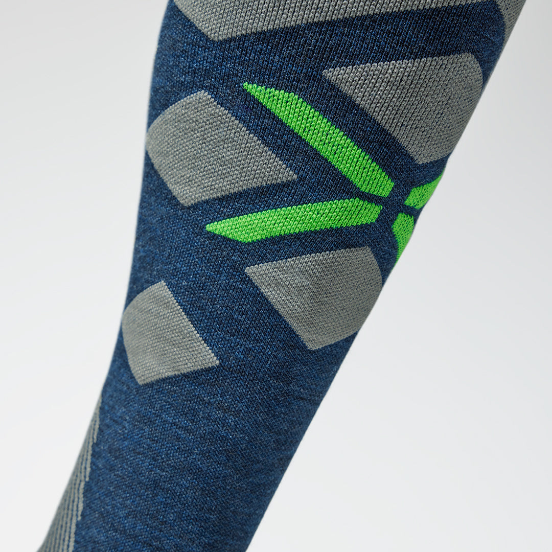 Close up of blue high compression sock with a green logo on the shin.