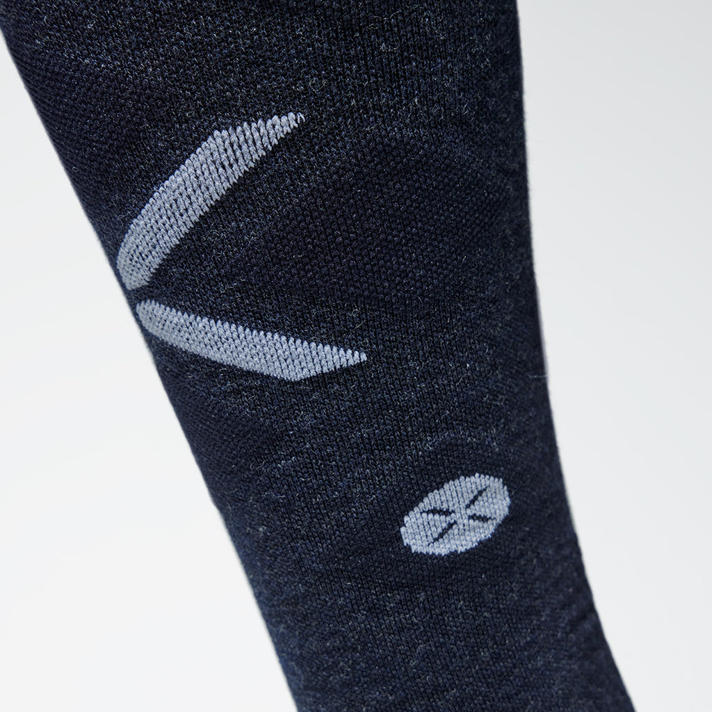 Close up of a high compression sock with a white logo on the shin.