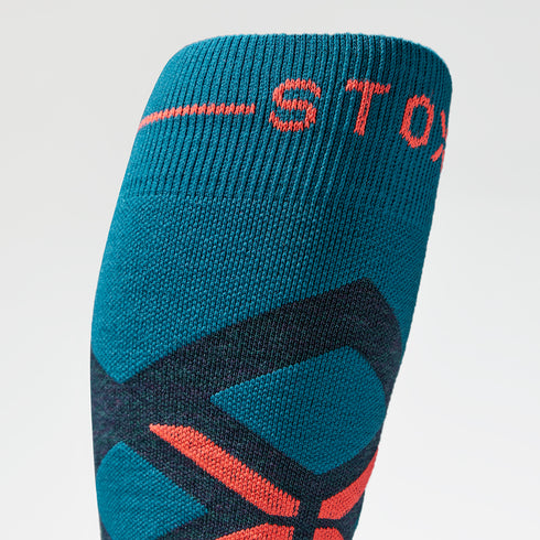 Close up of a high teal compression sock with red details. 