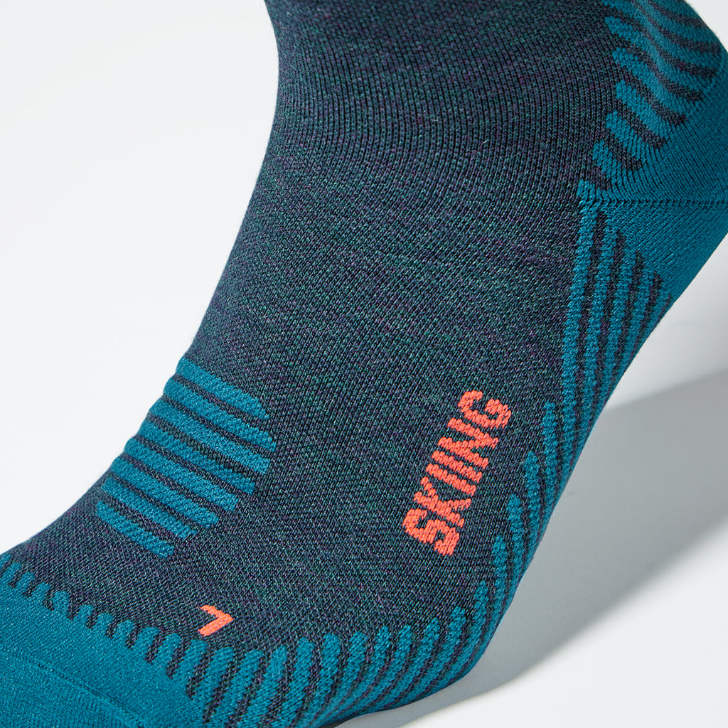 Close up of a left footed teal compression sock with red accents.
