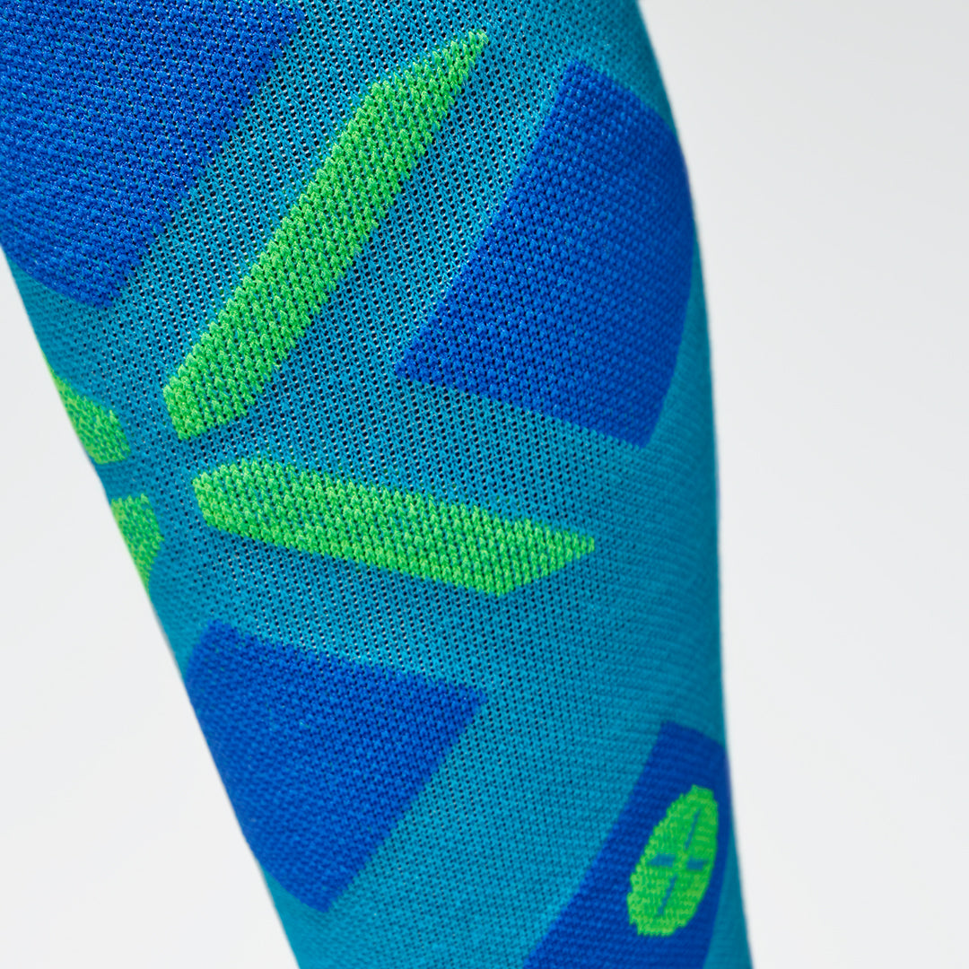 Close up of a high turquoise compression sock with a green logo.