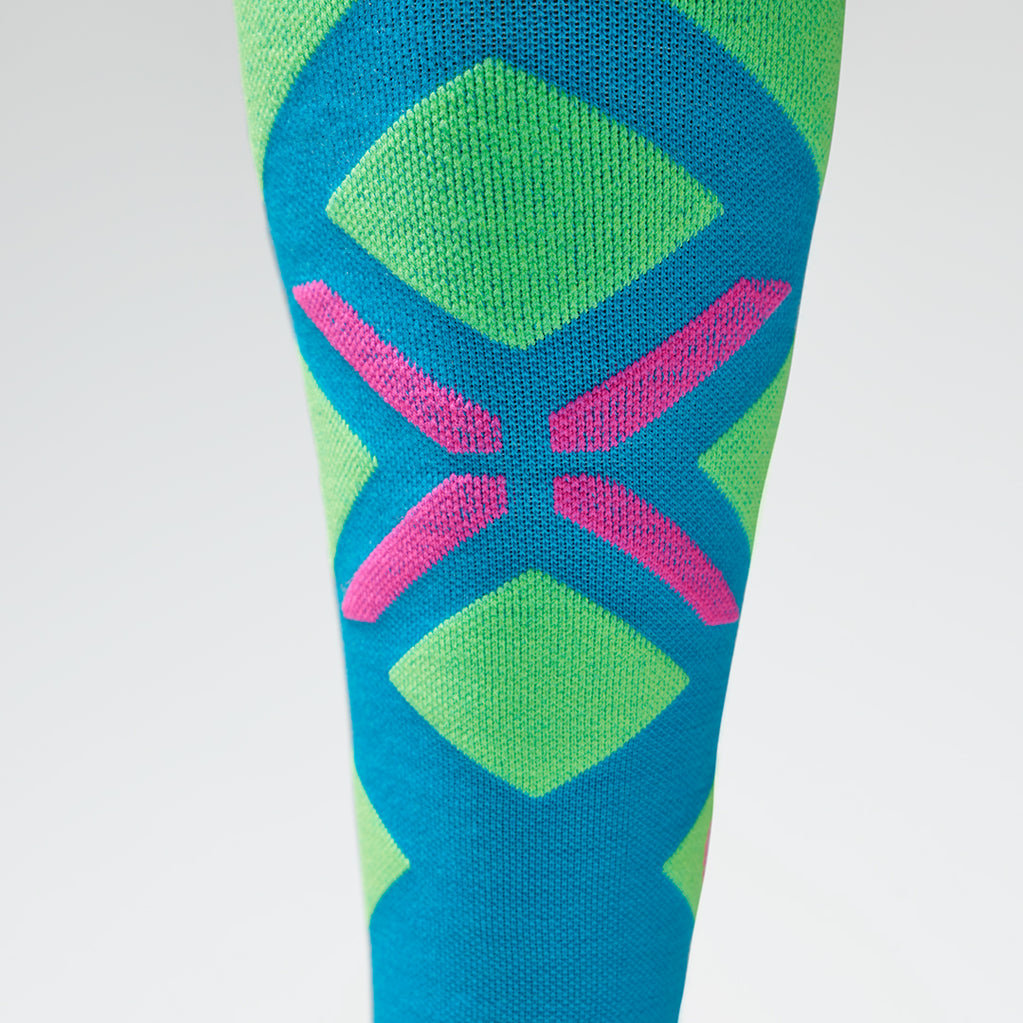 Close up a high compression sock in turquoise with a pink logo on the shin.