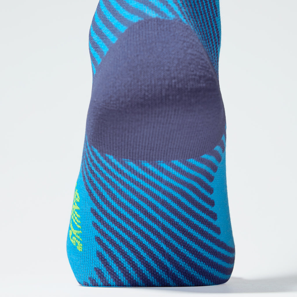 Zoomed in view of a turquoise knee high compression sock with yellow details.