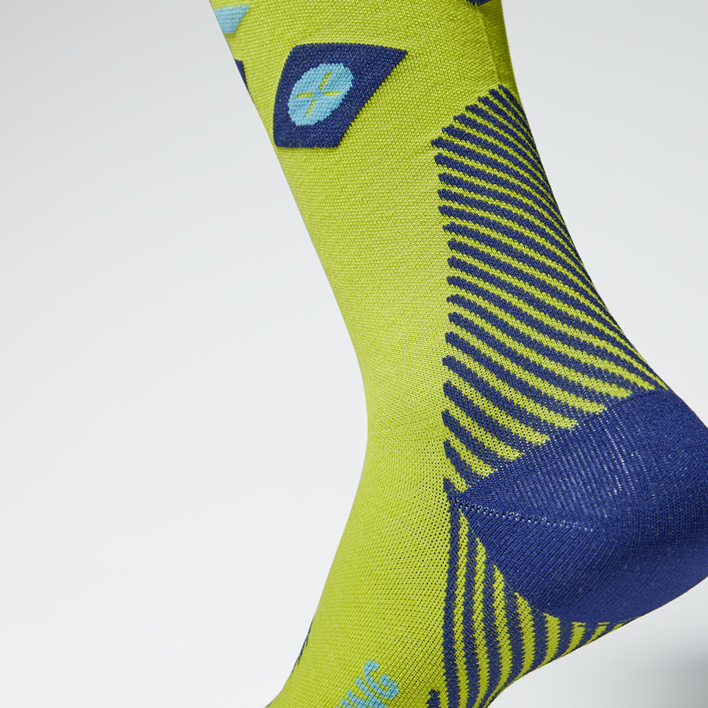 Close up of a yellow compression sock with a blue heel and lined details.