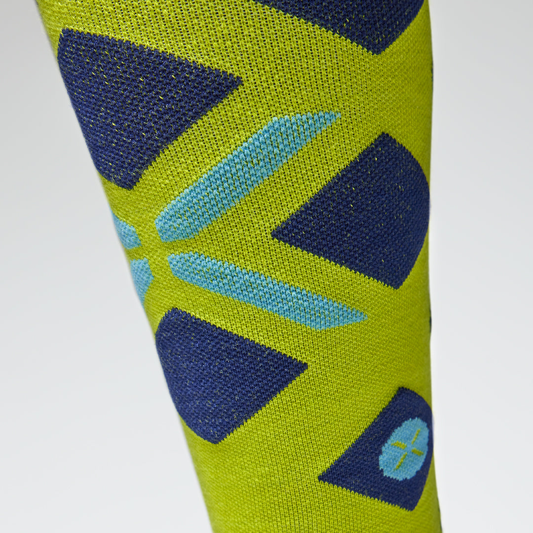Close up of a yellow high compression sock with a blue logo.