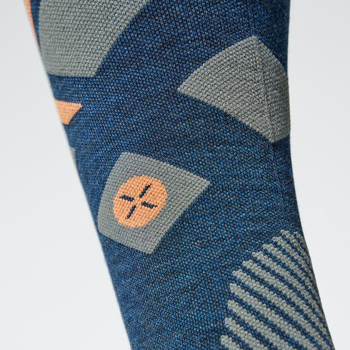 Close up of a blue compression sock with an orange logo.