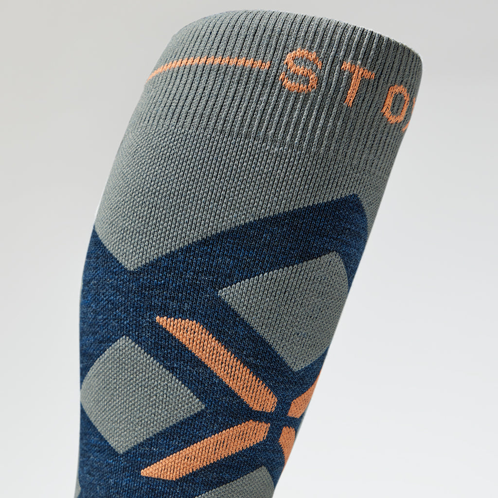 Close up of a blue high compression sock with orange accents.