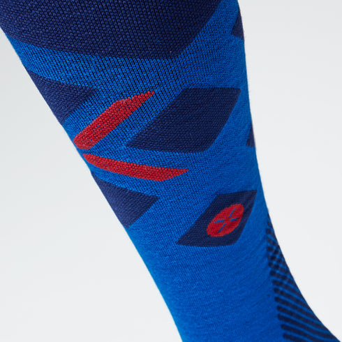 Close up of a cobalt compression sock with a red logo.