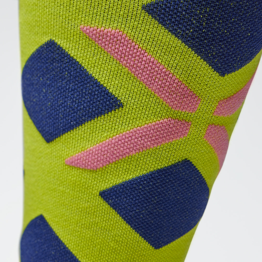Close up of a yellow compression sock with blue accents and a pink logo.