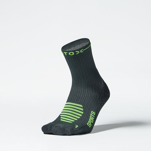 Front of an ankle high compression sock in dark grey with green accents. 