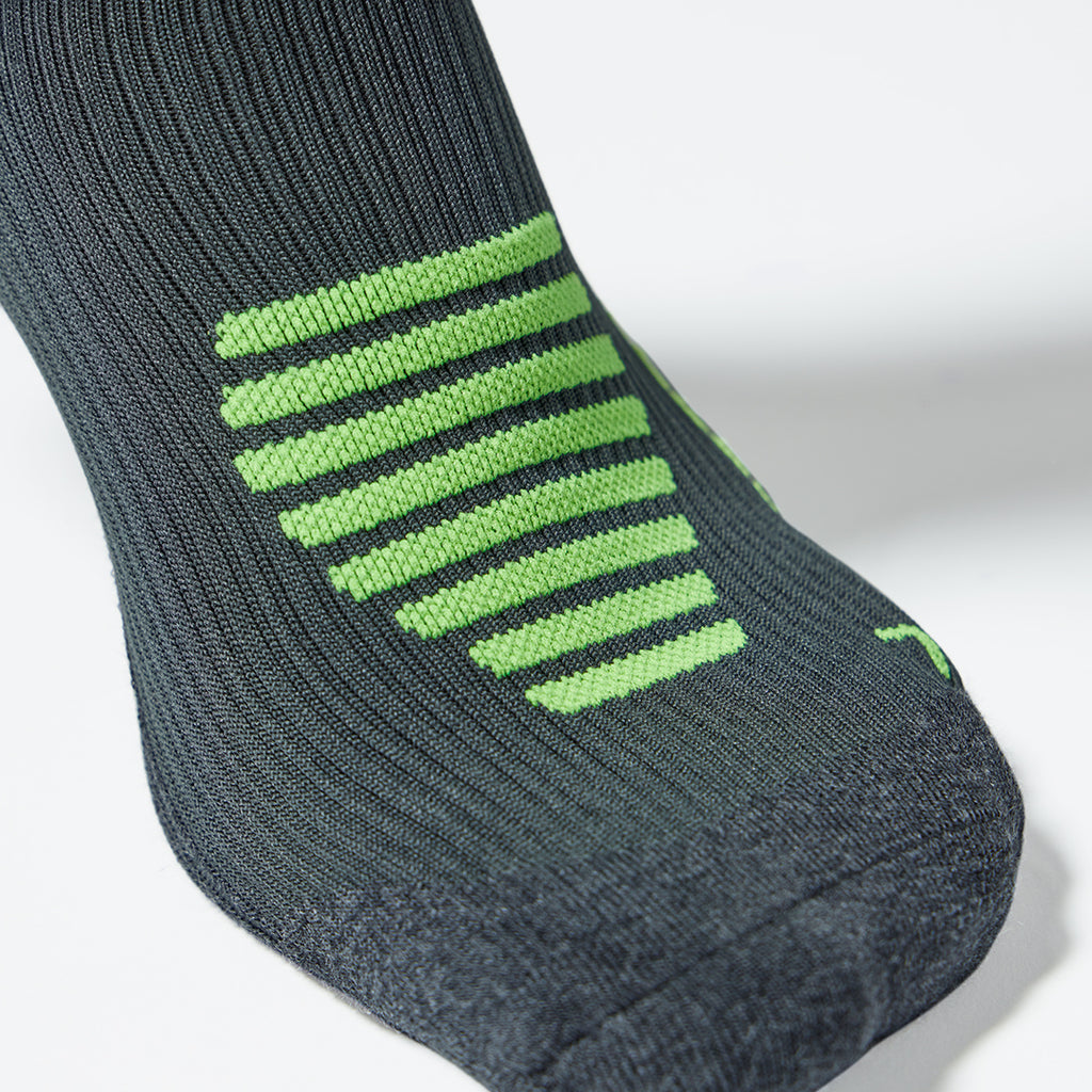 Close up of a compression sock in dark grey with green details. 