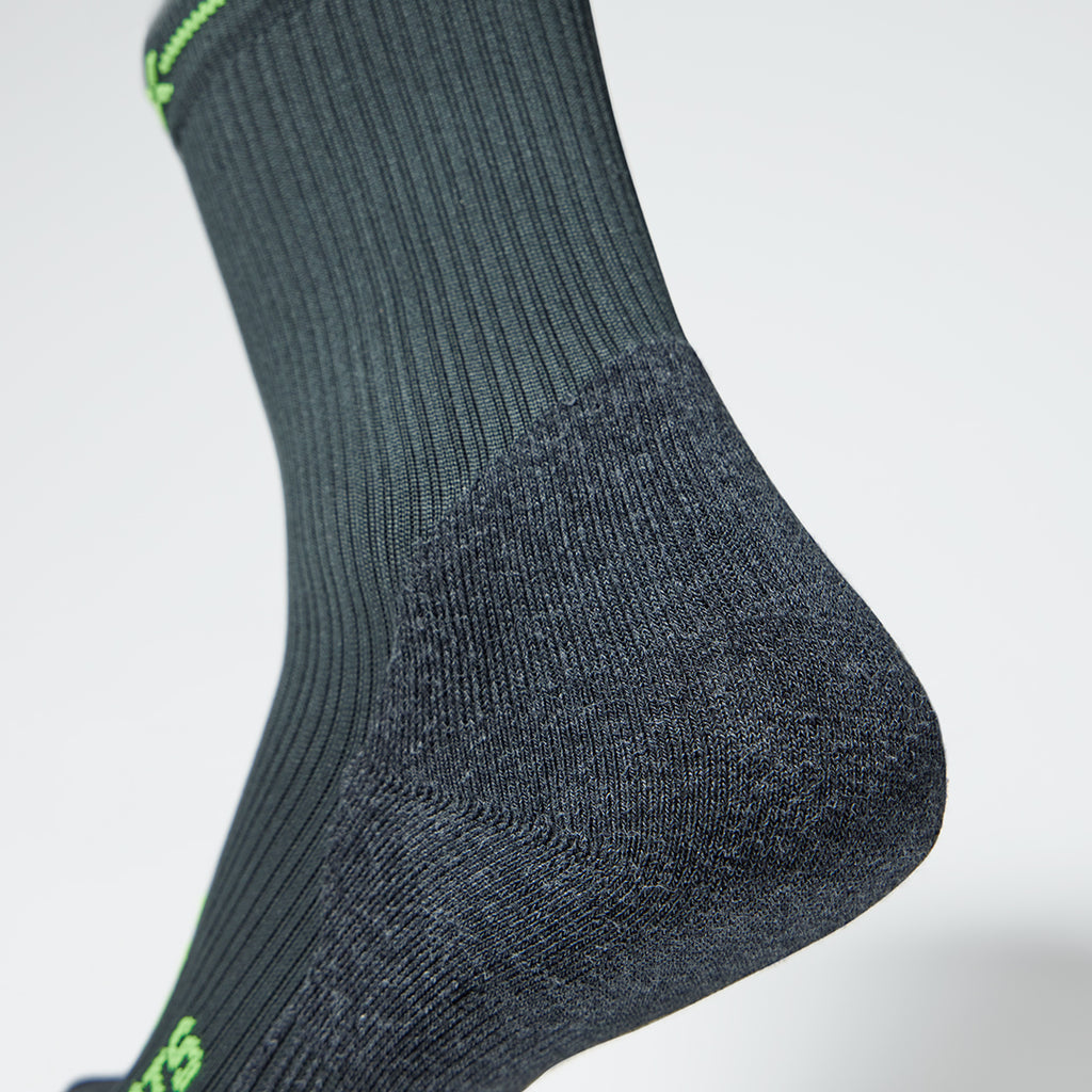 Close up of the back of a compression sock in dark grey with green accents.