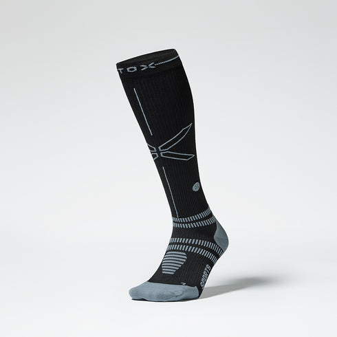 A knee high compression sock in black with grey details from the front.