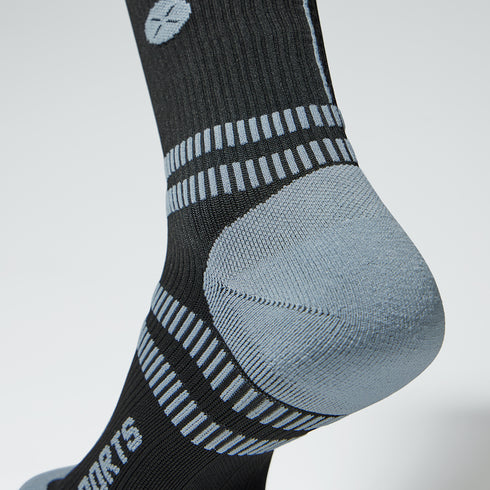 Close up of a compression sock in black with a grey logo and heel.