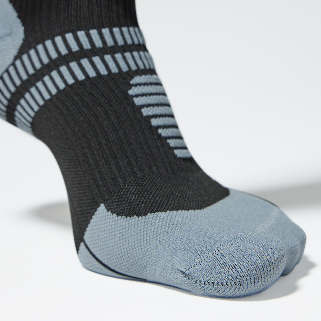 Zoomed in on a compression sock in black with grey details. 