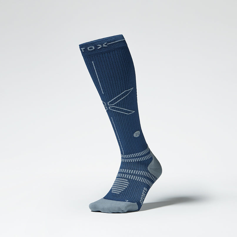 A blue knee high compression sock with grey details from the front.