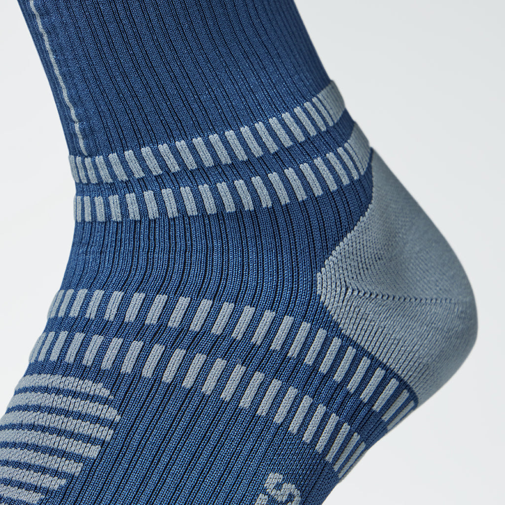 Close up of a blue compression sock with a grey heel. 