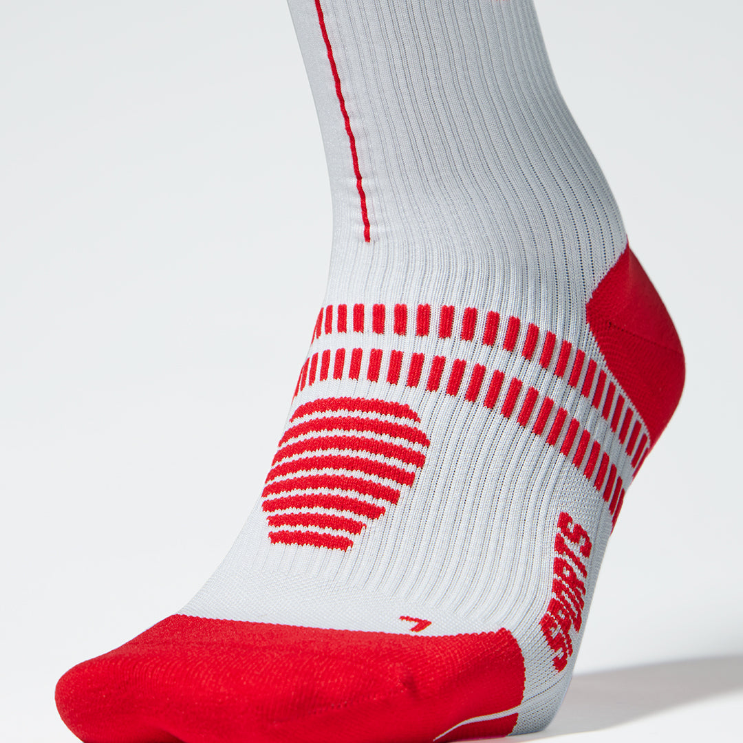 Close up of a white compression sock with red lined details.