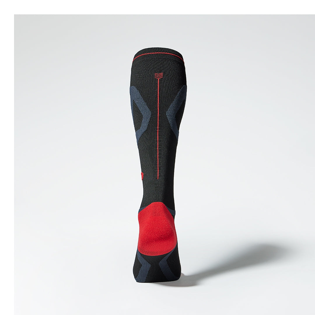Back view of a black compression sock with red details.