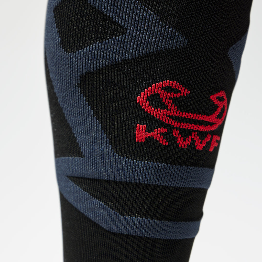 Close up of a black knee high compression sock with a red KWF logo.