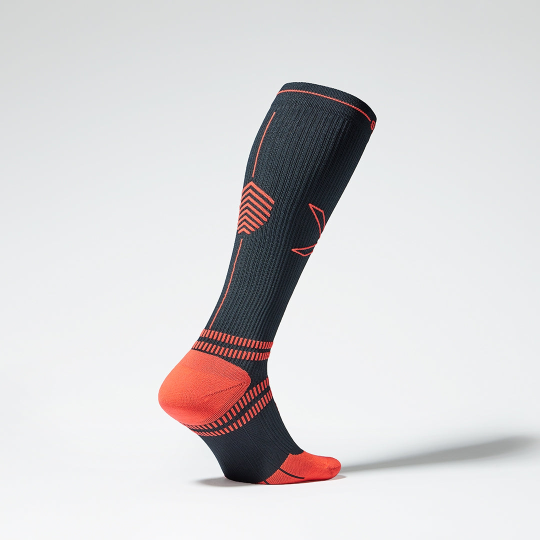 A standing navy blue knee high compression sock from the front.