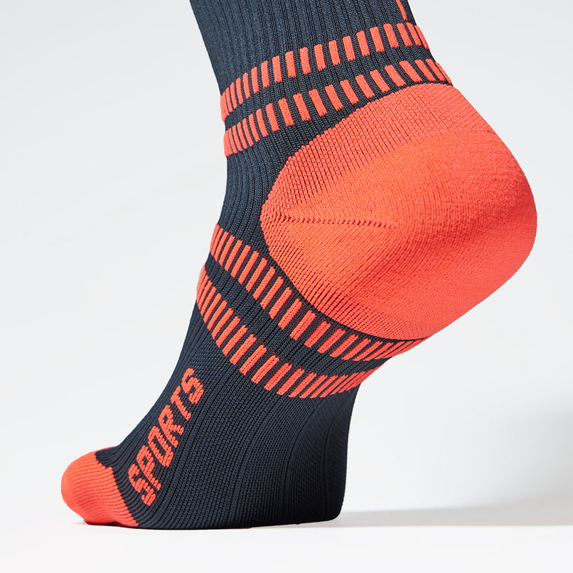 A navy blue compression sock with orange heel close up.