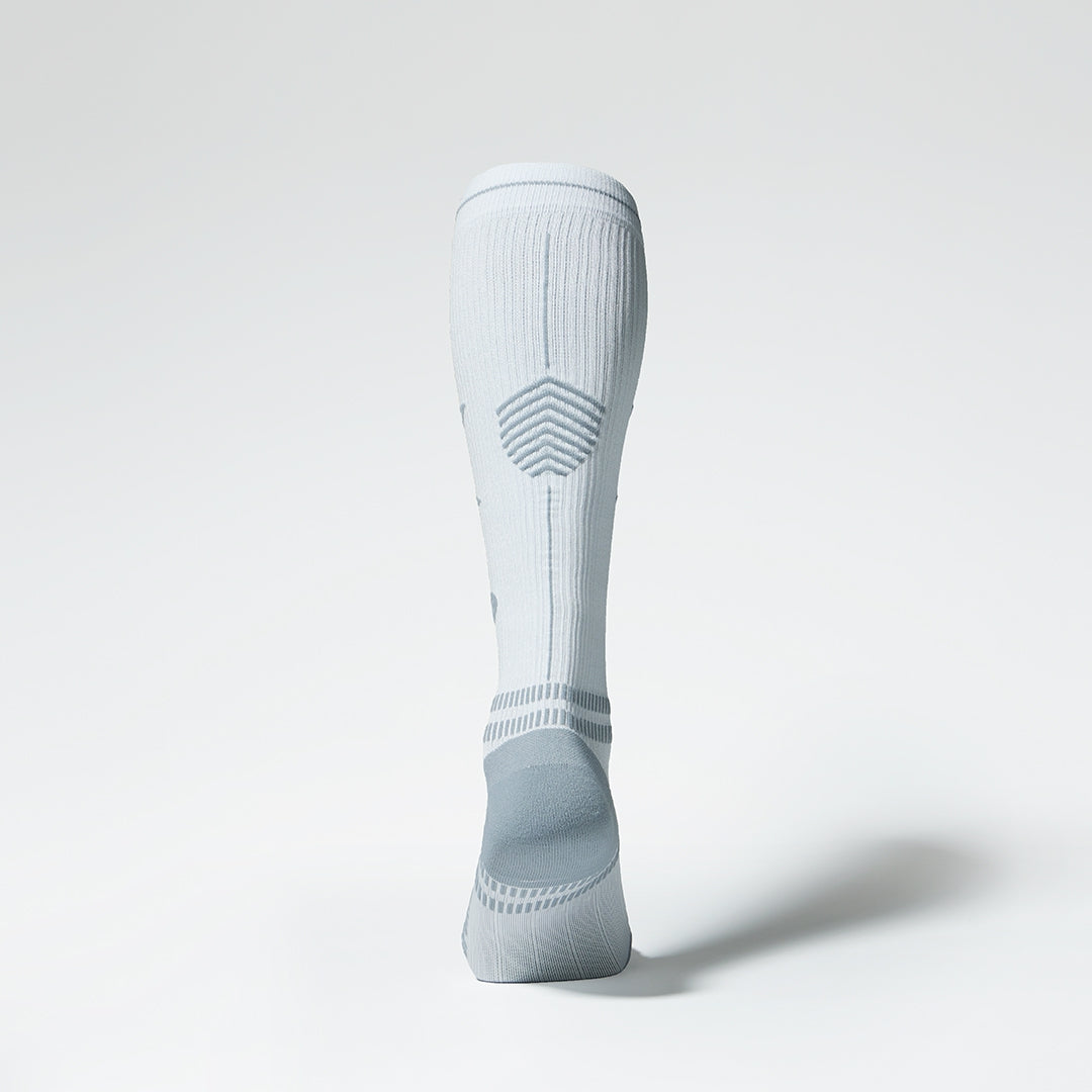 Back view of a knee high compression sock in white with grey accents. 