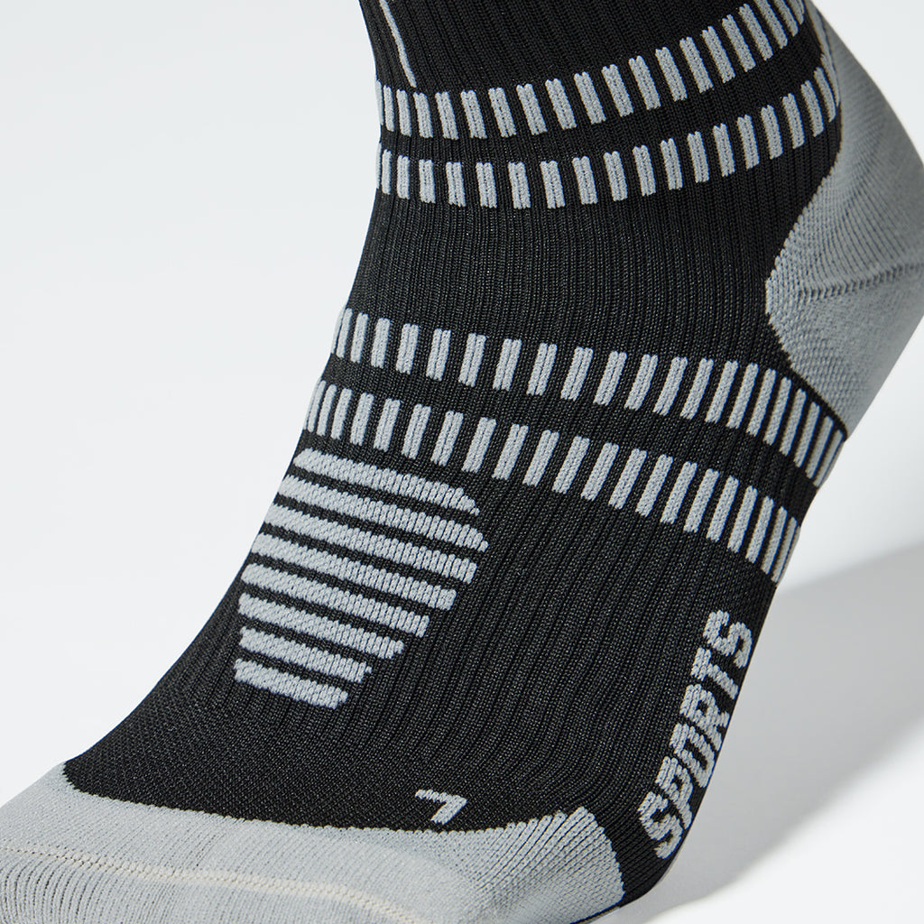 Back view of a knee high compression sock in black with grey accents.