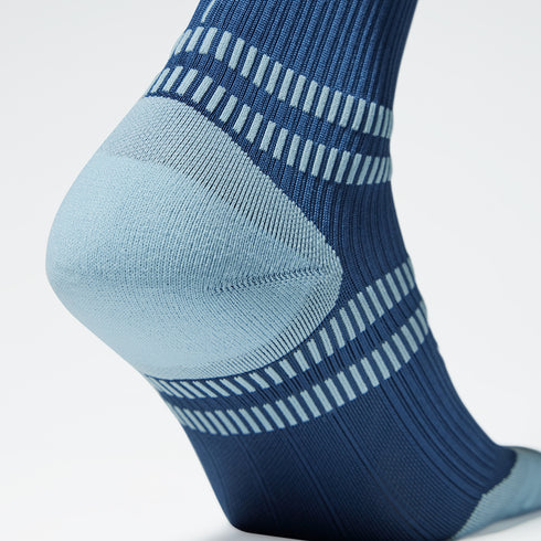 Close up of a blue knee high compression sock with a grey heel.