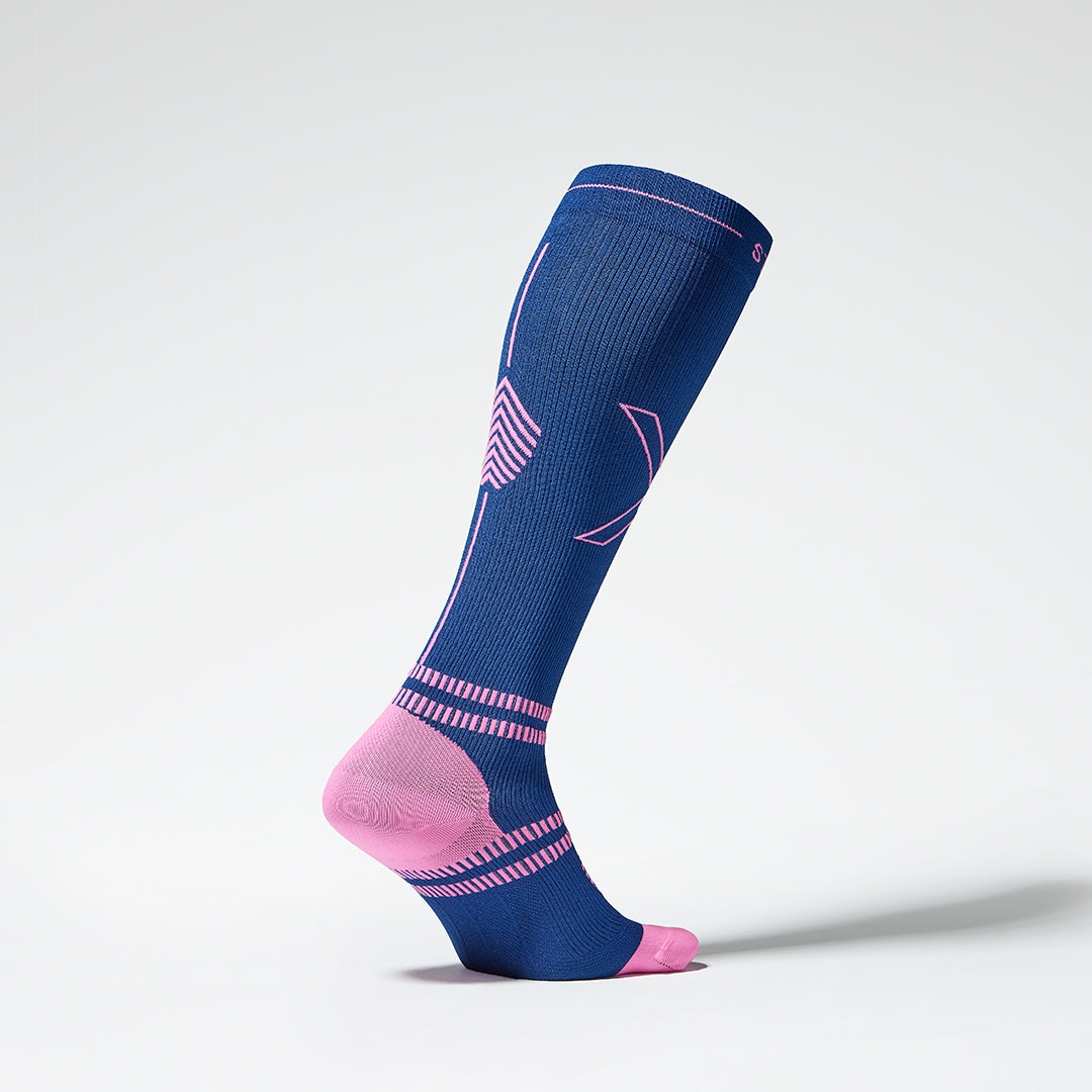 Side view of a dark blue coloured knee high compression sock in dark blue with pink accents. 