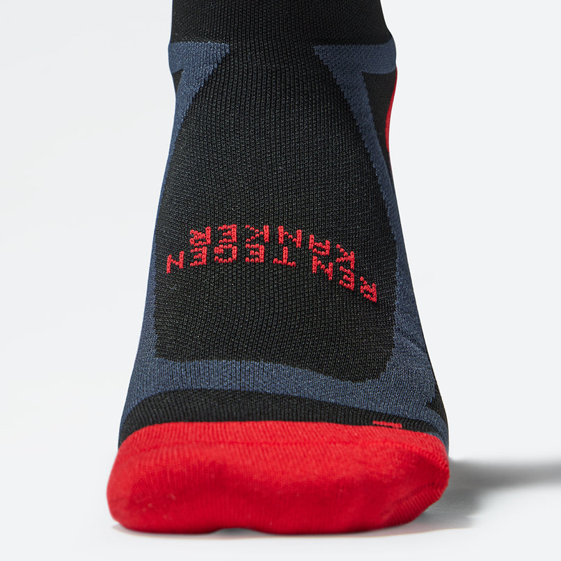 Close up of the front of a compression sock in black with red accents. 