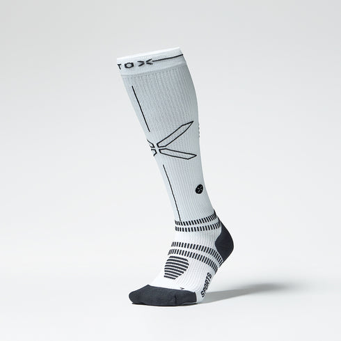 Front view of a white colored knee high compression sock with black details. 