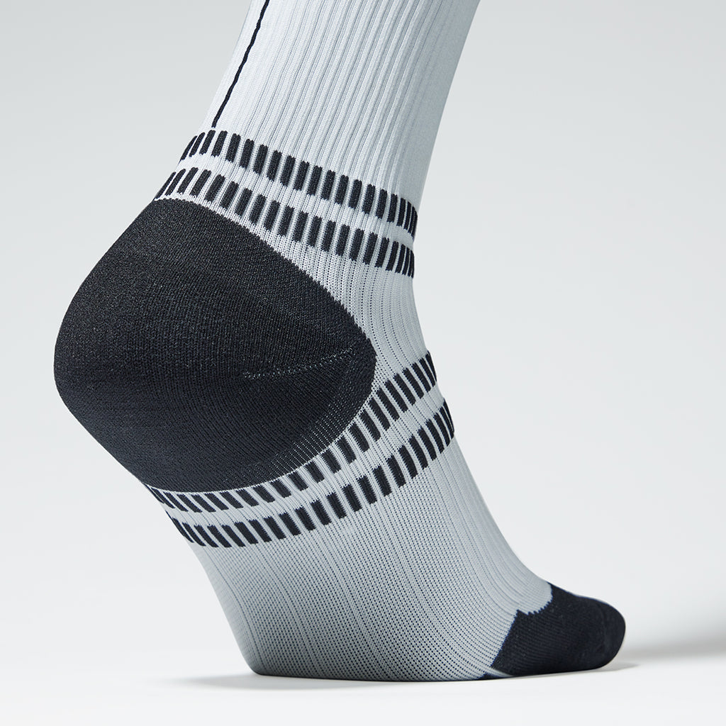 Close up of a knee high compression sock in white with black accents.