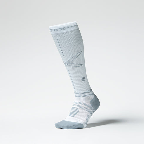 Front view of a white colored knee high compression sock with grey accents.