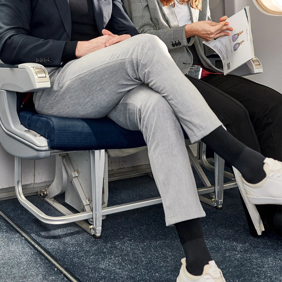 Legs of a couple sitting in an airplane wearing dark blue socks. 