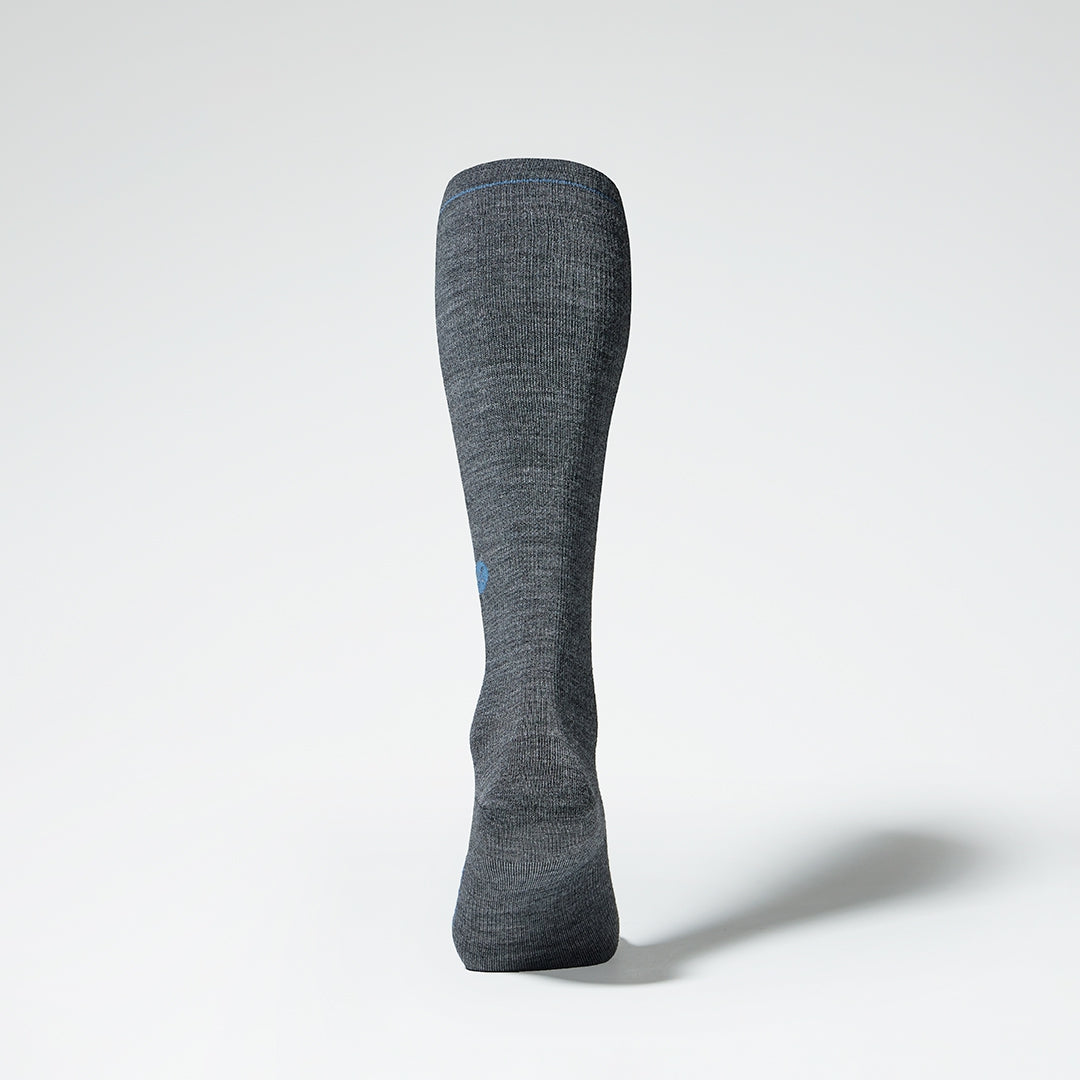 Back view of a grey knee high compression sock with blue details.