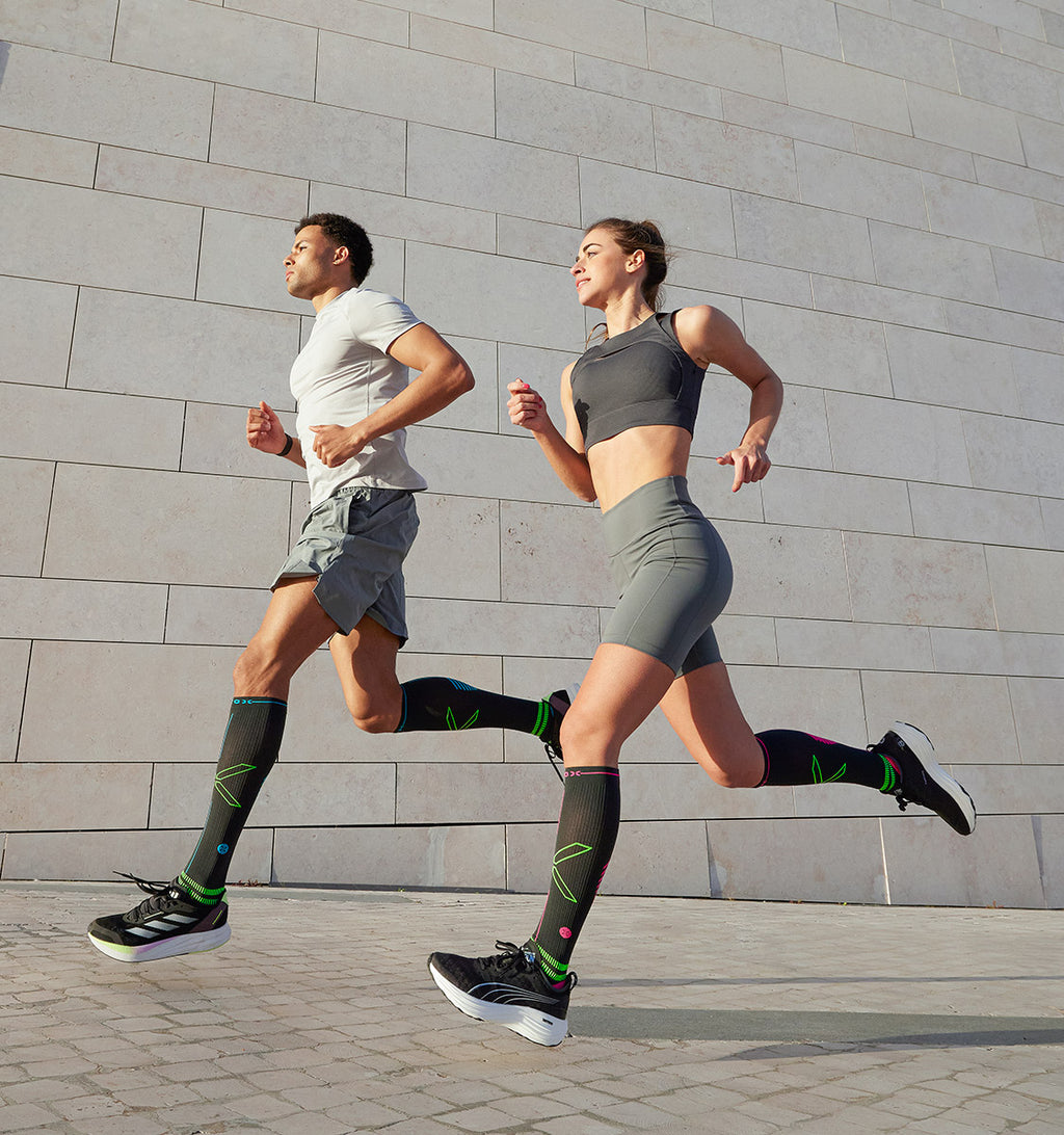 Man and woman running in front of grey wall.