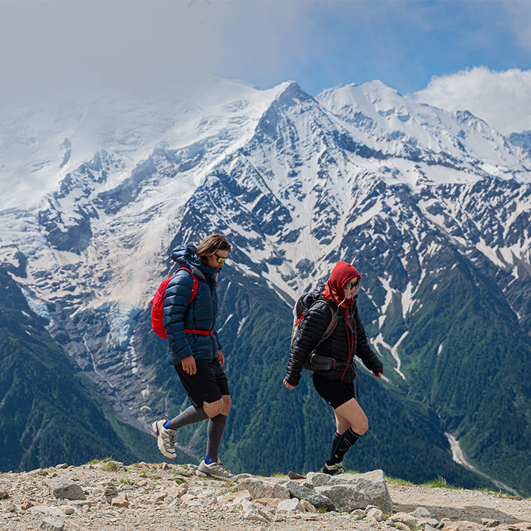 Two people walking over rocks.