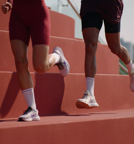 Two people running across red stairs. 