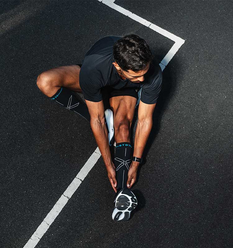 Person stretching on a black track with white lines