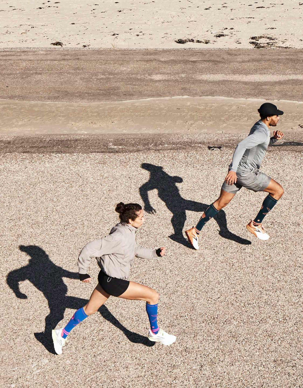 Two people running with their shadows behind them.