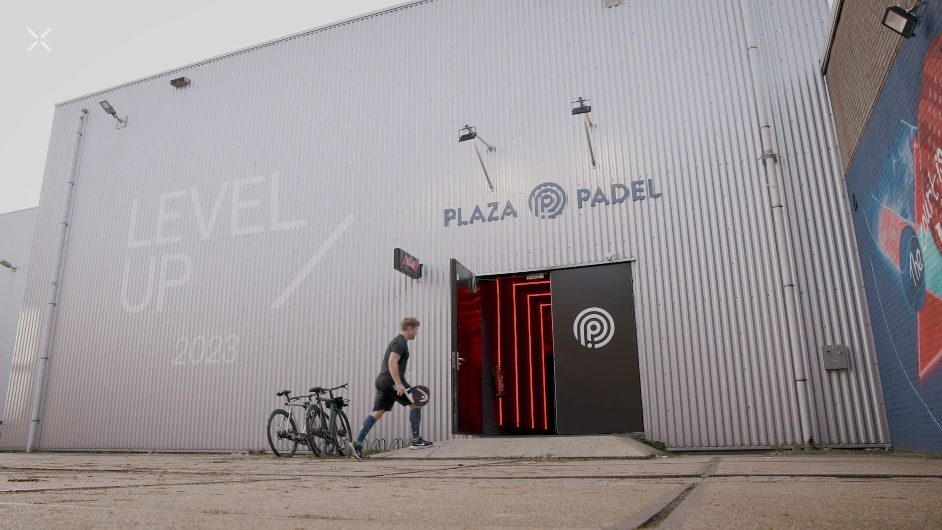 Sporter walking into a grey building.